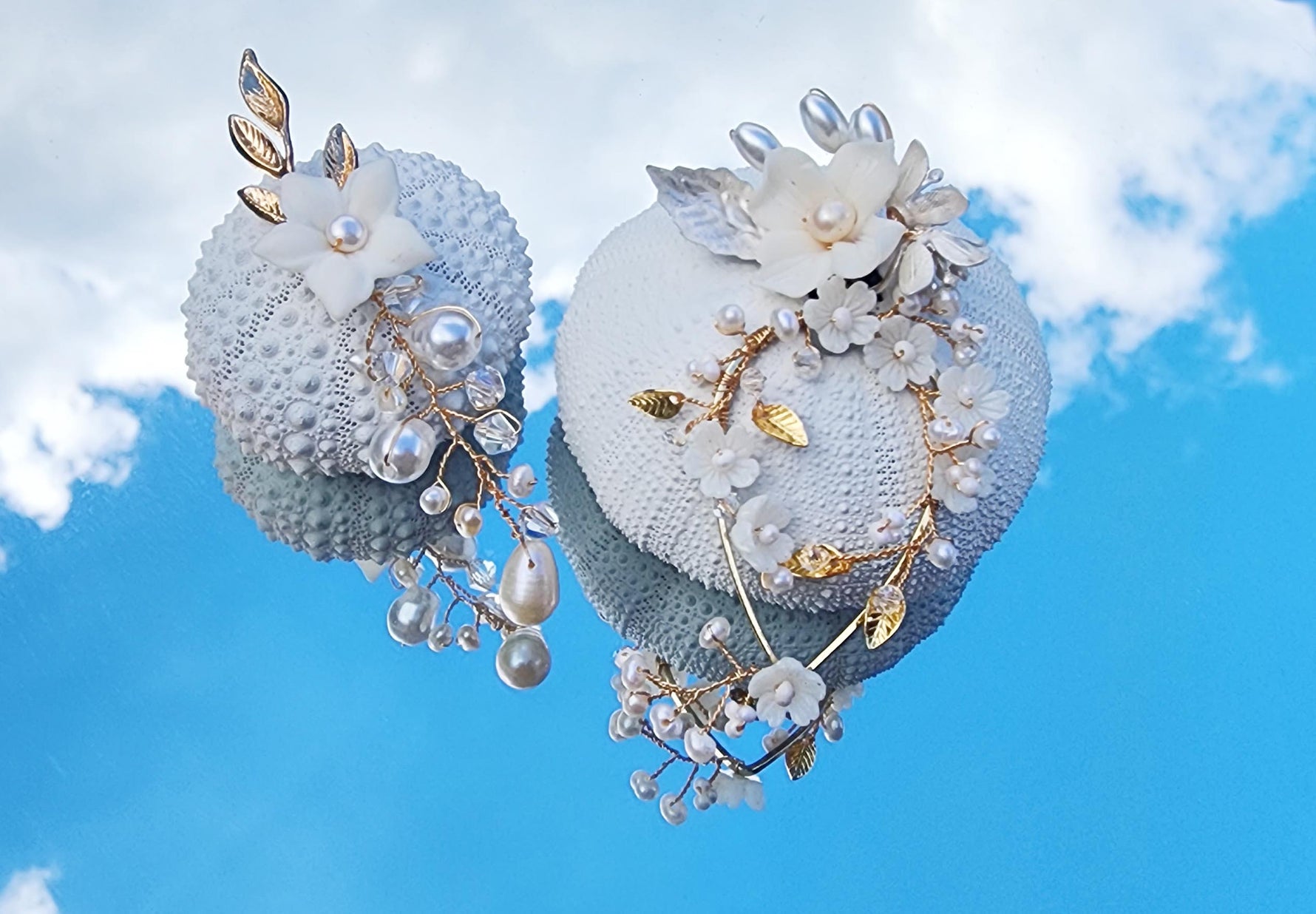 Handmade bridal earrings with freshwater pearls, porcelain flowers, and gold wire details, displayed against a blue sky background
