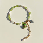 Bracelet with green avocado charm and pearl beads on a beige background
