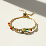 Gold bracelet with colorful charms on a light background