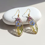 Pair of floral earrings on a white stone surface