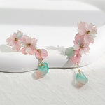 Floral earrings with pink and green elements on a white background
