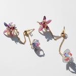 Pair of floral earrings with gold chains on a light background