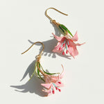 Floral earrings with pink flowers and gold hooks on a light background