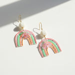 Rainbow-shaped earrings with floral details on a white background