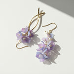 Gold earrings with purple floral designs on a white background