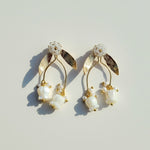 Pair of gold and pearl earrings on a light background