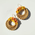 Woven hoop earrings with floral accents on a light background
