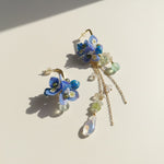 Floral earrings with blue flowers and chain details on a light background