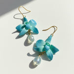 Pair of blue flower-shaped earrings with gold hooks on a light background
