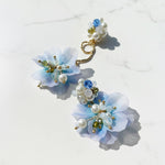 Pair of floral earrings with pearls and gemstones on a light background