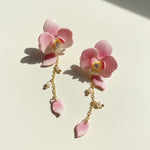 Pink floral earrings with gold chains on a light background