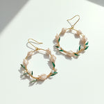 Gold hoop earrings with floral and leaf details on a white background