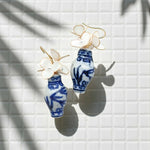 Earrings with blue and white ceramic design on a light tiled background