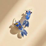 Blue glass earrings with floral designs on a beige background