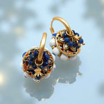 Gold earrings with blue and white stones on a light blue background