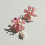 Pink floral earrings with pearl and gemstone details on a light background