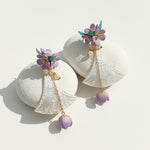 Hand-carved shell fan earrings with lilac flowers and pearl accents on white stones.