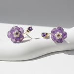Pair of purple flower earrings on a white surface