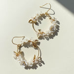 Gold hoop earrings with floral and leaf designs on a light background