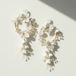 Floral earrings with white flowers and gold accents on a light background
