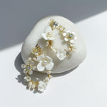 Porcelain floral and pearl hoop earrings on white background with sunlight and shadow.