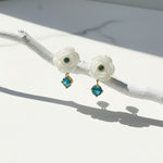 Pair of floral earrings with turquoise stones on a white surface