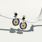 Gold and navy blue beaded dangle earrings with circular woven design hanging from crystal studs.