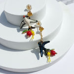 Colorful bird-shaped earrings on a white stand