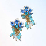 Decorative earrings with blue and white floral elements on a light blue background
