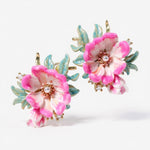 Pair of floral earrings with pink flowers and gold accents on a white background