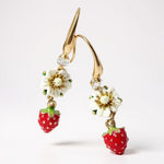 Gold earrings with strawberry and flower designs on a white background