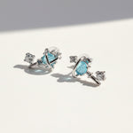 Pair of silver earrings with blue gemstones on a light background