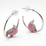 Silver hoop earrings with pink cockatoo charms on a white background