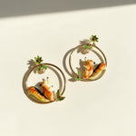 Pair of hoop earrings with squirrel designs on a beige background