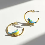 Gold hoop earrings with bird designs on a white background