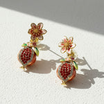 Pair of floral and fruit-themed earrings on a light background