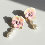 Pair of floral earrings with pearl accents on a light surface