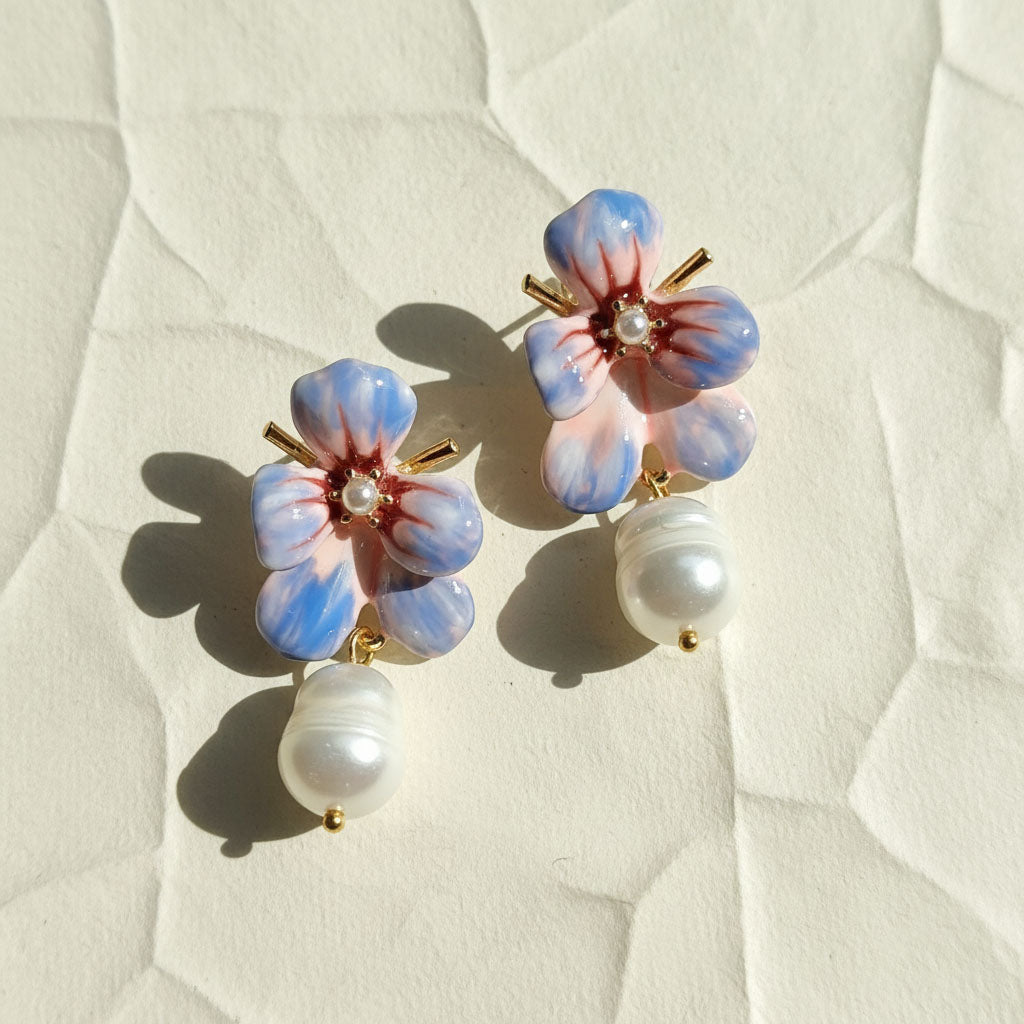 Floral earrings with pearl accents on a textured white surface