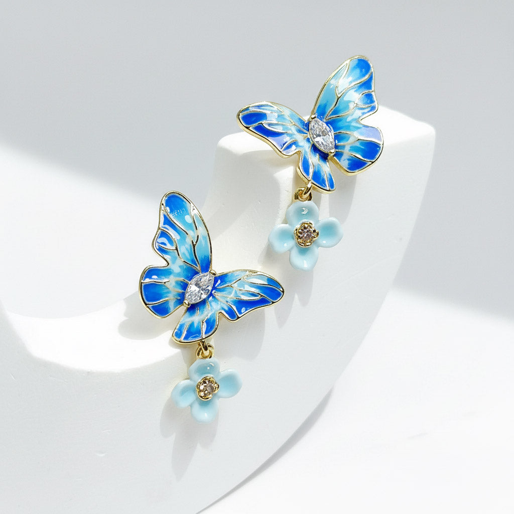 Blue butterfly earrings with flowers on a white stand