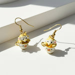 Earrings with mouse in a teacup design on a light surface