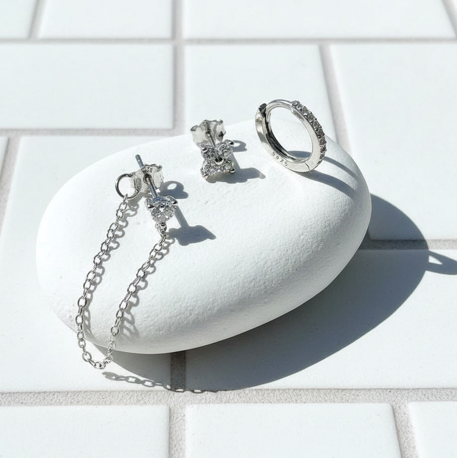 Silver earrings on a white stone surface with a light background
