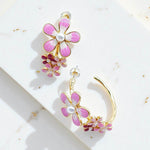 Pink flower-shaped earrings with gold accents on a white surface