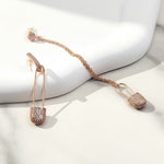 Rose gold earrings with a chain on a white surface