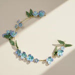 Floral headband with blue flowers and green leaves on a beige background