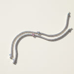 Two moissanite heart tennis bracelets in pink and white center stones on a light background