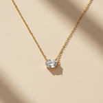 2ct gold moissanite pendant necklace in sunlight on beige surface