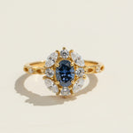 Gold-plated sterling silver ring with oval blue sapphire center and marquise-cut diamond halo
