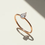 Rose gold pear cut moissanite solitaire ring on white background