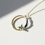 Gold necklace with a circular pendant featuring a bird design on a white background