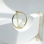 Gold necklace with a round pendant featuring a white cockatoo design on a white background